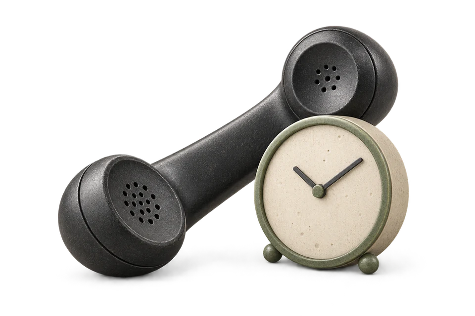Telephone receiver leaning beside a small analogue clock